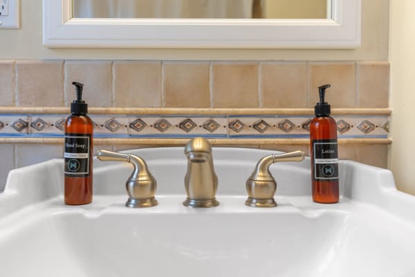 A bathroom sink with hand soap and lotion bottles on either side.