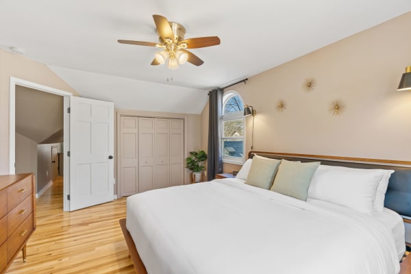 Cozy bedroom with a large window, neatly made bed, and stylish decor.