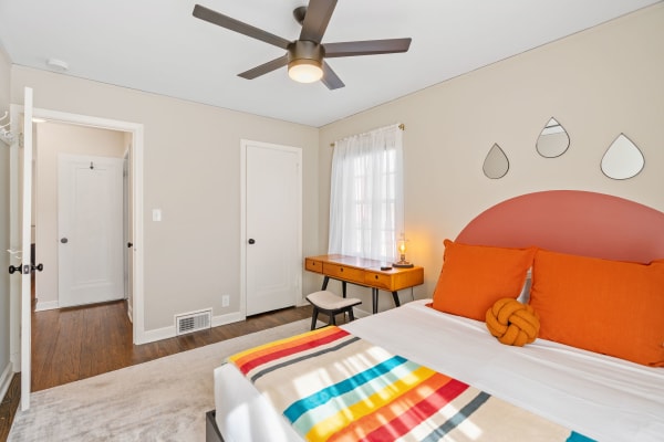 Modern bedroom with colorful bed accessories and a wooden desk.