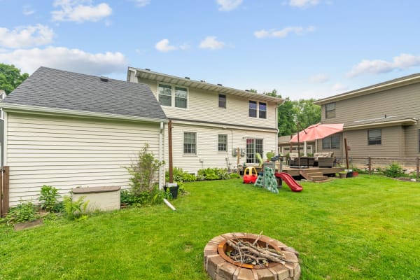 A backyard featuring a fire pit, children's playset, and outdoor seating.