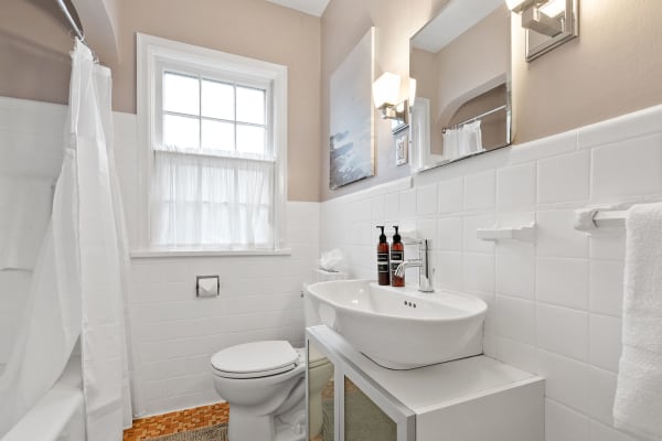 Modern bathroom with an oval sink, white walls, and a shower curtain.