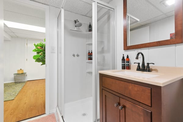 Interior view of a modern bathroom with a glass shower and wooden vanity.