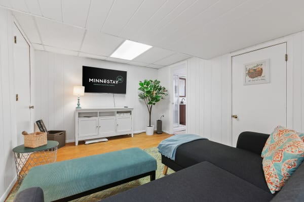 Cozy living room with a TV, indoor plant, and sectional couch.