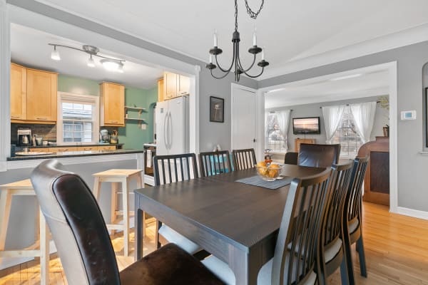 Bright dining area featuring a modern table, chandelier, and an adjacent kitchen.