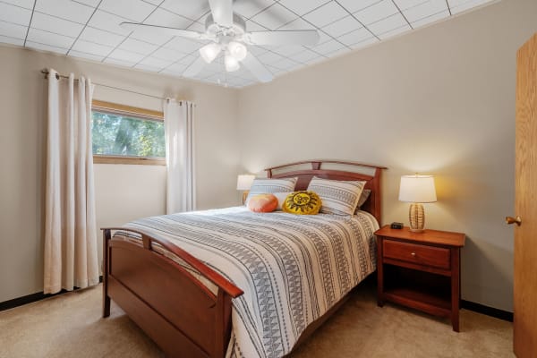 Cozy bedroom with a wooden bed, striped bedding, and natural light from the window.