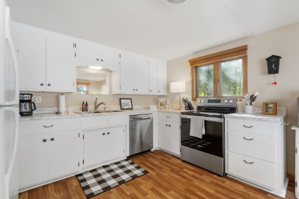 Contemporary kitchen with white cabinets, marble countertops, and stainless steel appliances.