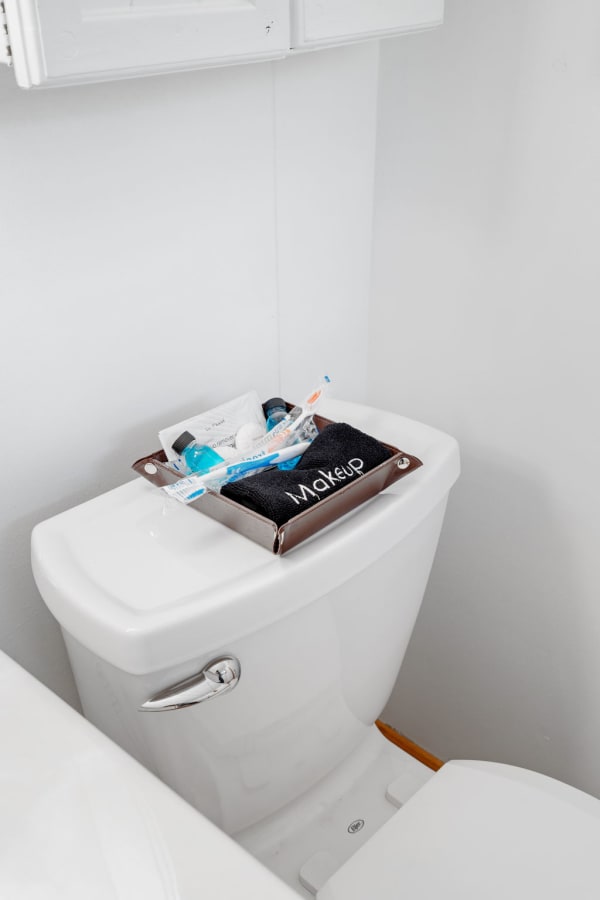 Makeup essentials arranged on a toilet tank in a neat bathroom.