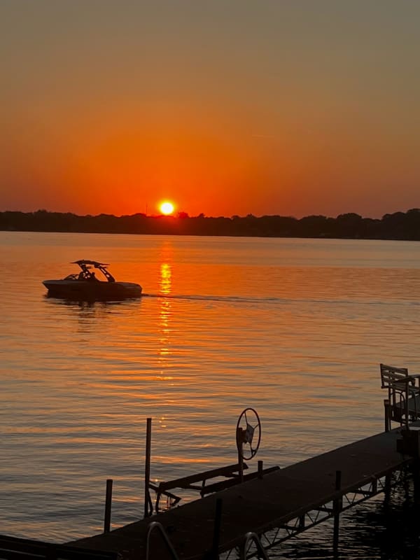 Sunset over a lake with a boat and a wooden dock