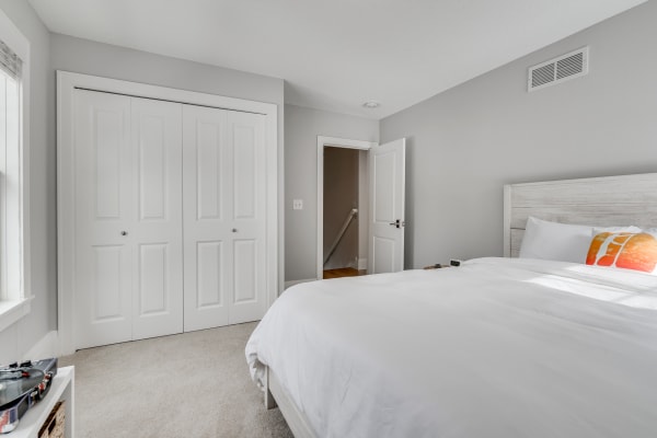 Cozy bedroom with a white bed, gray walls, and natural light.