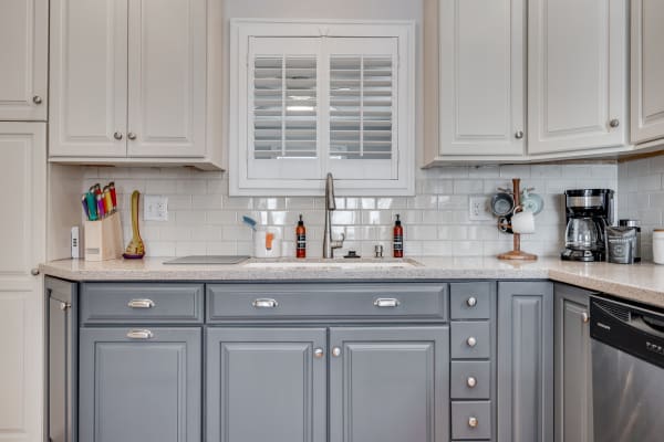 A cozy kitchen featuring grey cabinets, a modern sink, and colorful kitchen utensils.