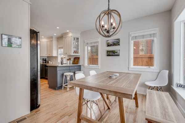 Contemporary kitchen-dining area with a round chandelier and wooden dining table.