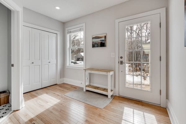 A bright entryway featuring a white console table, gray walls, and a snow-covered view through the glass door.