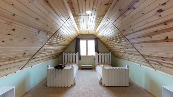 An attic room with two twin beds and a wooden ceiling.