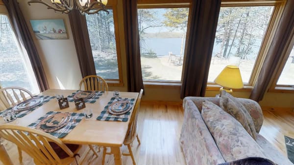 Dining area with wooden table set for a meal and a view of the lake.