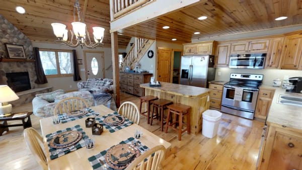 A cozy, rustic kitchen and living area with wooden furniture and a stone fireplace.