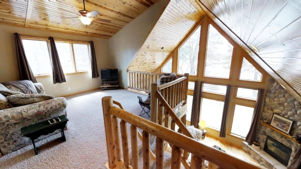 A cozy living room with wooden elements, large windows, and a floral couch.