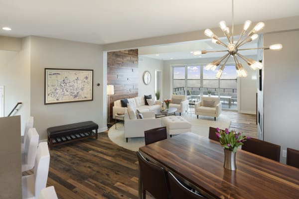 Modern living and dining room with large windows overlooking water and stylish decor.
