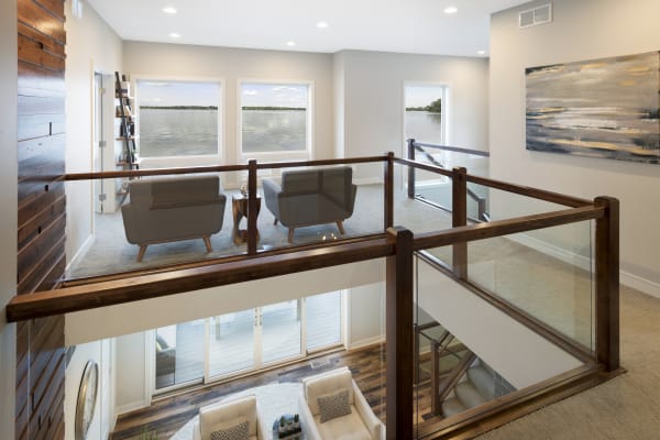 Modern loft overlooking a lake, featuring gray armchairs and wooden accents.