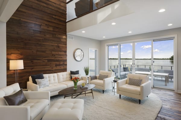 Stylish living room featuring a wooden accent wall and large windows overlooking a lake.