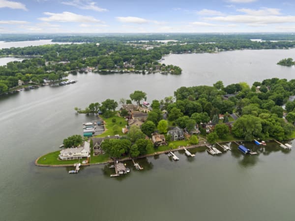 A scenic aerial view of a lakeside community featuring homes, green trees, and boats on the water.