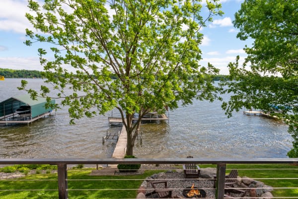Lakeside view with docks and a fire pit surrounded by trees.