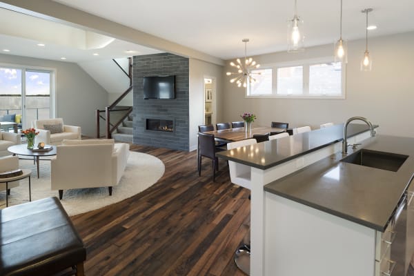 An open-concept living area featuring a kitchen, dining table, and lounge with large windows.