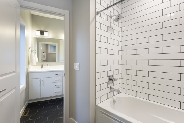 A modern bathroom featuring a white bathtub, subway tile and hexagonal tile flooring.
