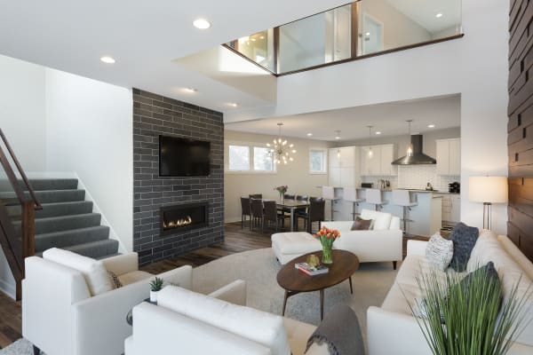 A modern living room with light sofas, a black stone fireplace, and a contemporary kitchen setting.