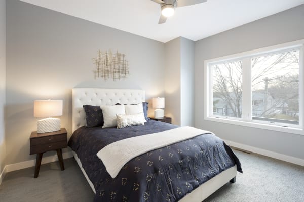 Modern bedroom featuring a tufted bed, decorative pillows, and natural light through large windows.