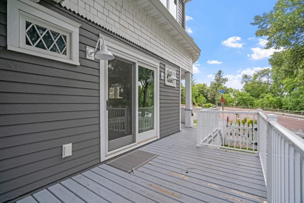 Exterior view of a modern house with gray siding and white accents, featuring a porch and sliding glass door.