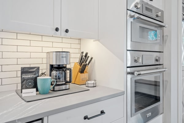 Modern kitchen with KRUPS coffee maker, blue mug, and stainless steel appliances.