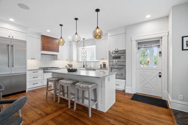 Contemporary kitchen with white cabinets, wooden accents, and an island seating area.