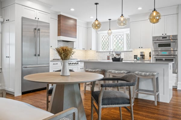 Modern kitchen with white cabinetry, stainless steel appliances, and a round dining table.