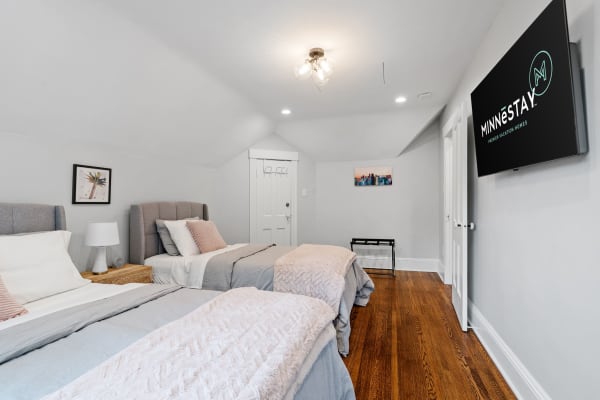Cozy modern bedroom with two beds, decorative pillows, and a mounted TV.