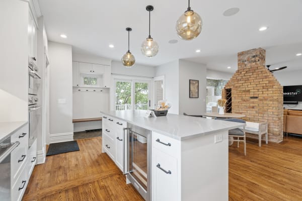 Modern kitchen featuring an island, pendant lights, and an exposed brick fireplace.