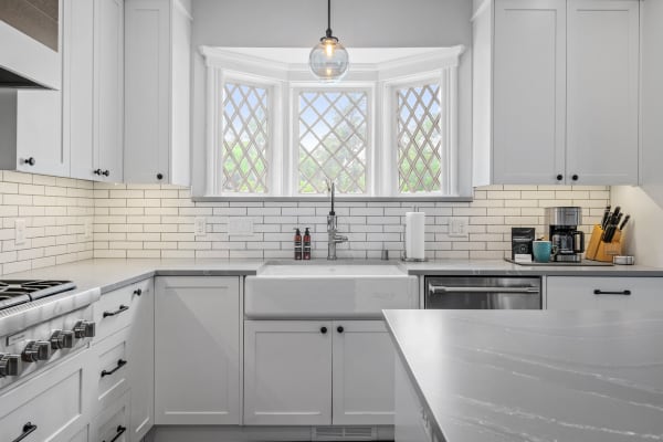 Modern kitchen featuring a farmhouse sink and diamond-patterned bay window.