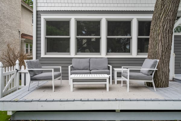 Outdoor seating area with grey cushions and white furniture on a deck.
