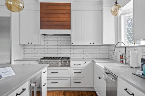 Modern kitchen featuring white cabinets, a wooden accent wall, and stainless steel appliances.
