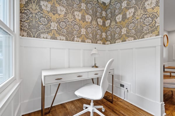 Cozy home office space with a white desk and floral wallpaper.