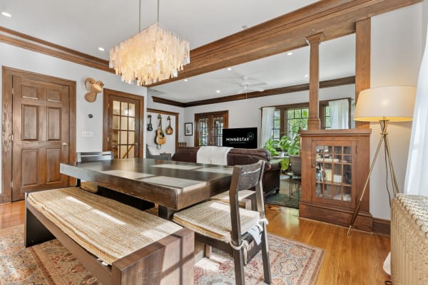 Interior view of a cozy living space with a dining table and leather sofa, decorated with plants and art.
