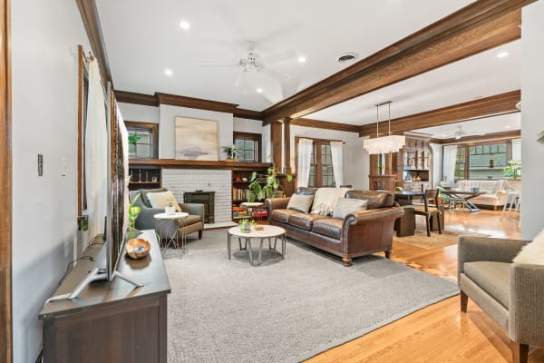 A stylish living room featuring a leather sofa, gray rug, and white-brick fireplace with modern decor.