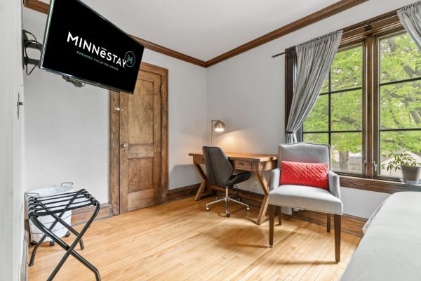 Cozy room with a desk, chair, and natural light from a large window.