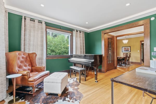 Room featuring a green wall, brown leather chair, grand piano, and wooden flooring.
