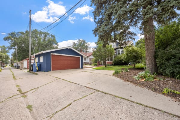 A quiet alley with a blue garage, tree, and well-kept plants