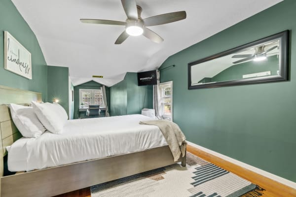 A well-decorated bedroom featuring a green color scheme, a modern bed, and a desk area.