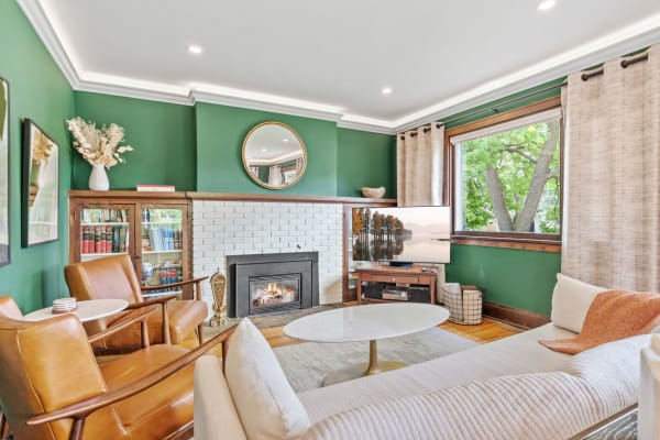 A cozy living room featuring green walls, a fireplace, and modern furniture.