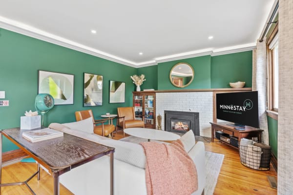 Cozy living room with green walls, fireplace, and modern furniture.