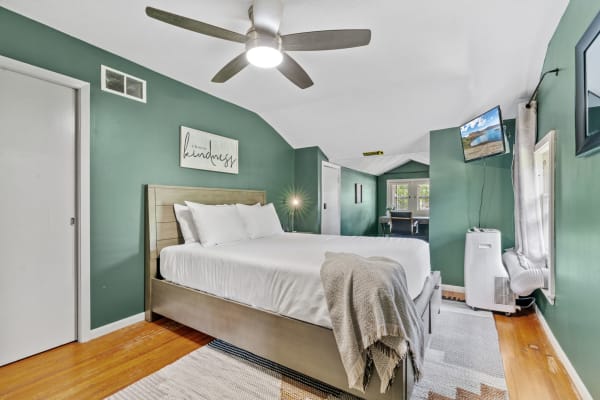 A modern bedroom featuring a bed, decorative artwork, and a workspace area.