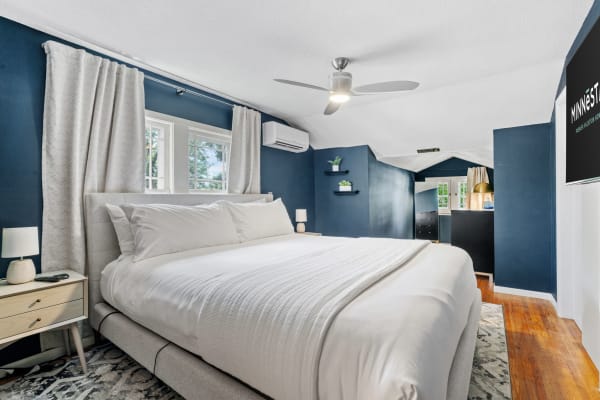 Cozy bedroom featuring navy walls, a plush bed, and modern decor.