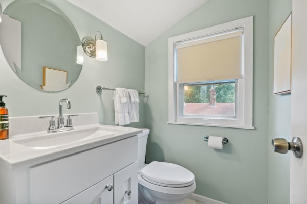 A stylish bathroom with green walls, a white vanity, and contemporary lighting.